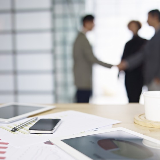 close-up of business items with people meeting in background.